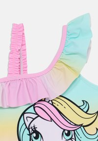 Maillot de bain avec un dégradé de couleurs pastel, doté d'une bretelle froncée rose, orné d'un graphique de licorne en noir avec des détails de crinière multicolores.