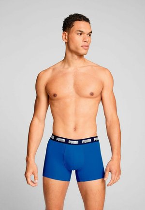 Blue boxer briefs made of stretchy fabric, featuring a black waistband with "PUMA" text. Smooth texture and fitted design.