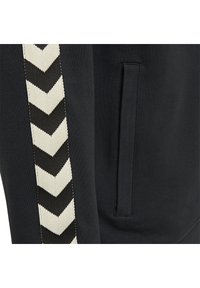 Felpa nera con cappuccio caratterizzata da un motivo a zig-zag in avorio e nero lungo il lato, con un dettaglio di tasca nascosta sul davanti.