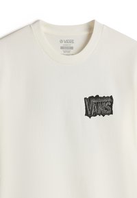 Lockere T-Shirt aus off-weißem Baumwollstoff mit einem schwarzen, abgenutzten Vans-Logo auf der linken Brustseite. Klassisches Rundhalsdesign.