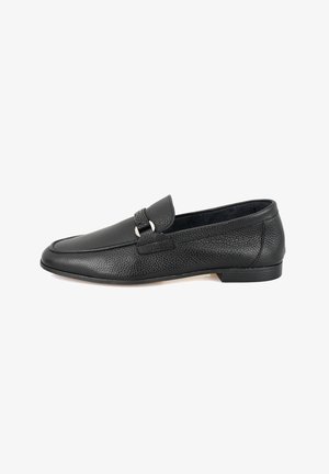 Schwarze Lederloafer mit strukturiertem Finish, abgerundeter Zehenpartie und einem dekorativen Riemen mit silberfarbenen Hardware-Akzenten. Flache Absatzgestaltung.