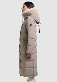 Palton puffer lung, bej, cu guler înalt și glugă căptușită cu fleece, având fermoar și buzunare laterale, cu un model matlasat.