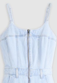 Ανοιχτό μπλε denim αμάνικη μπλούζα με ρυθμιζόμενους ιμάντες, φερμουάρ μπροστά, ραφές διακοσμητικές και θηλιές για ζώνη στη μέση.