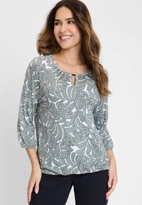 Grüne und weiße Bluse mit Blattmuster, rundem Halsausschnitt, Schlüssellochdetail und 3/4-Ärmeln. Weicher Stoff mit lässiger Passform.
