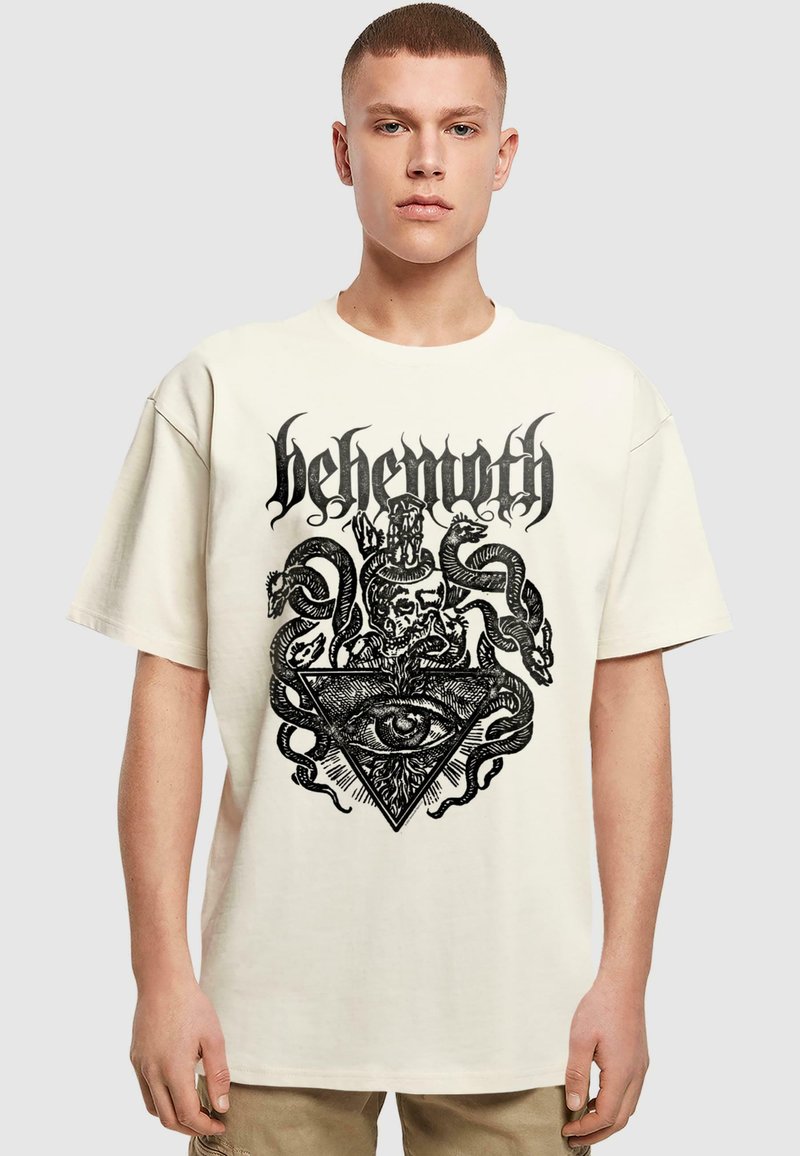 Cremefarvet kortærmet T-shirt med et sort grafisk design, der indeholder en trekant, et øje, kranier og slanger, lavet af blødt bomuldsstof.