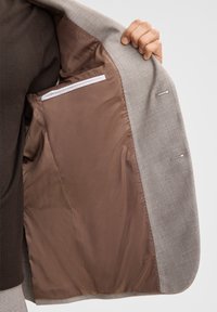 Grau Blazer mit glattem Stoffäußeren und braunem Satininnenfutter, ausgestattet mit einer Innentasche mit weißem Rand.
