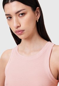 Canotta a coste rosa chiaro con scollatura rotonda e spalline larghe. La texture liscia e il design aderente esaltano la forma del capo.