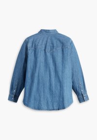 Chemise en denim bleu clair à manches longues, vue de dos, avec des poignets boutonnés et un empiècement pointu au niveau des épaules.