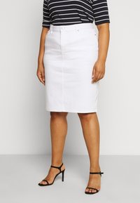 White denim pencil skirt with a fitted silhouette, standard waist, and front pockets, paired with a black and white striped top and black heels.