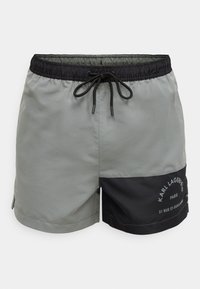 Férfi úszónadrág: szürke anyag fekete derékrésszel, húzózsinórral és oldalsó panelekkel. A fekete részen logónyomat található, elegáns kialakítású, könnyű anyagból.