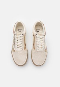 Paar beiger Wildleder- und Canvas-Sneaker mit weißen Schnürsenkeln und mehrfarbigem Camouflage-Muster an den Seiten, von oben betrachtet.