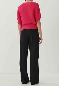 Růžový pletený svetr s žebrovaným lemem a krátkým rukávem, kombinovaný s volnými černými kalhotami. Hladká textura a uvolněný střih.