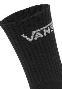 Schwarze Stricksocke mit geripptem Design, die am oberen Rand ein auffälliges graues "VANS"-Logo zeigt.