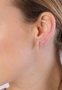Boucles d'oreilles géométriques en argent avec une longue barre fine et une pièce angulaire plus petite ; design élégant et minimaliste avec une finition polie.