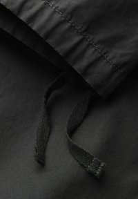 Tessuto in nylon nero con orlo arricciato e cordoncino. La superficie è liscia con una finitura opaca.
