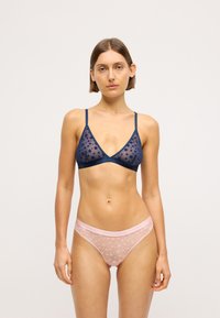 Tumes sheer-silma bralette tähe mustriga ja õhukeste rihmadega; sobivad roosad sheer-püksikud tähe kujunduse ja logo elastse vööga.