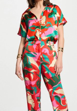 Ensemble coloré deux pièces composé d'une chemise à manches courtes boutonnée et d'un pantalon à jambes larges. Confectionné dans un tissu lisse avec un motif floral rouge, vert et rose.