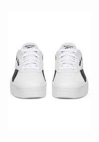 Fehér Reebok sportcipők fekete részletekkel, sima bőr felsőrésszel, perforált orral, lapos fehér fűzőkkel és vastag, texturált talppal.