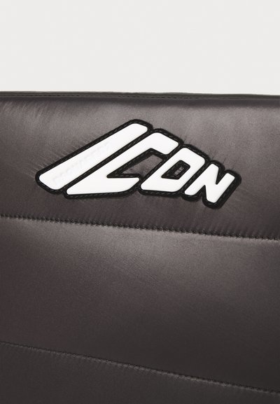 Sedile imbottito nero con una finitura lucida, caratterizzato da un logo bianco prominente "ICON" e dettagli di cucitura fine lungo i bordi.