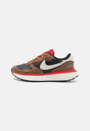 Baskets Nike marron, noir et rouge avec logo swoosh blanc, semelle blanche rembourrée et lacets marron sur fond uni.