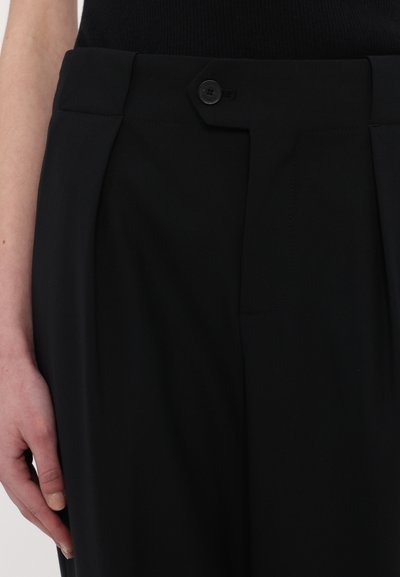 Pantalons tailleur noirs avec une texture lisse, dotés d'une fermeture à bouton unique et de plis avant pour un design structuré.