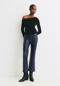 Czarna bluzka z odkrytymi ramionami połączona z wysokim stanem, granatowymi spodniami z sztucznej skóry w kształcie dzwonów oraz czarnymi, wysokimi botkami na obcasie. Gładka tekstura i dopasowany krój.