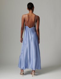 Μεταξωτό γαλάζιο μάξι φόρεμα με χαμηλή πλάτη, λεπτές τιράντες και ασύμμετρο τελείωμα. Διαθέτει λεία υφή και ευαίσθητα ραφές.
