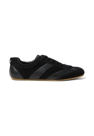 Zapatilla negra de perfil bajo con paneles de ante y cuero, cordones delanteros y suela de goma marrón claro, vista desde el lado exterior.