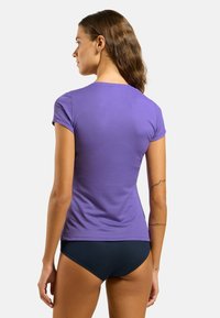 Purple fitted t-shirt made of smooth fabric, short sleeves, with a rounded neckline, paired with dark blue bikini bottoms, showing a close view from the back.