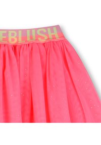 Ροζ φούστα από τούλι με φαρδιά ελαστική μέση που φέρει το όνομα "BLUSH" σε αντανακλαστικά κίτρινα γράμματα· ελαφρύ και στρωματοποιημένο σχέδιο με διακριτικά λαμπερά στοιχεία.