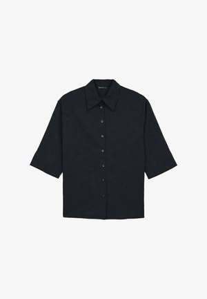 Chemise noire à manches courtes avec un col pointu, dotée d'une fermeture à boutons et d'un motif texturé sur l'ensemble du tissu.
