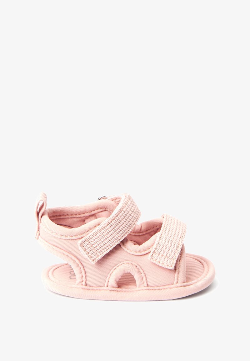 Sandale en tissu rose avec deux brides réglables en velcro, découpes rondes et semelle rembourrée. Texture douce et design flexible.