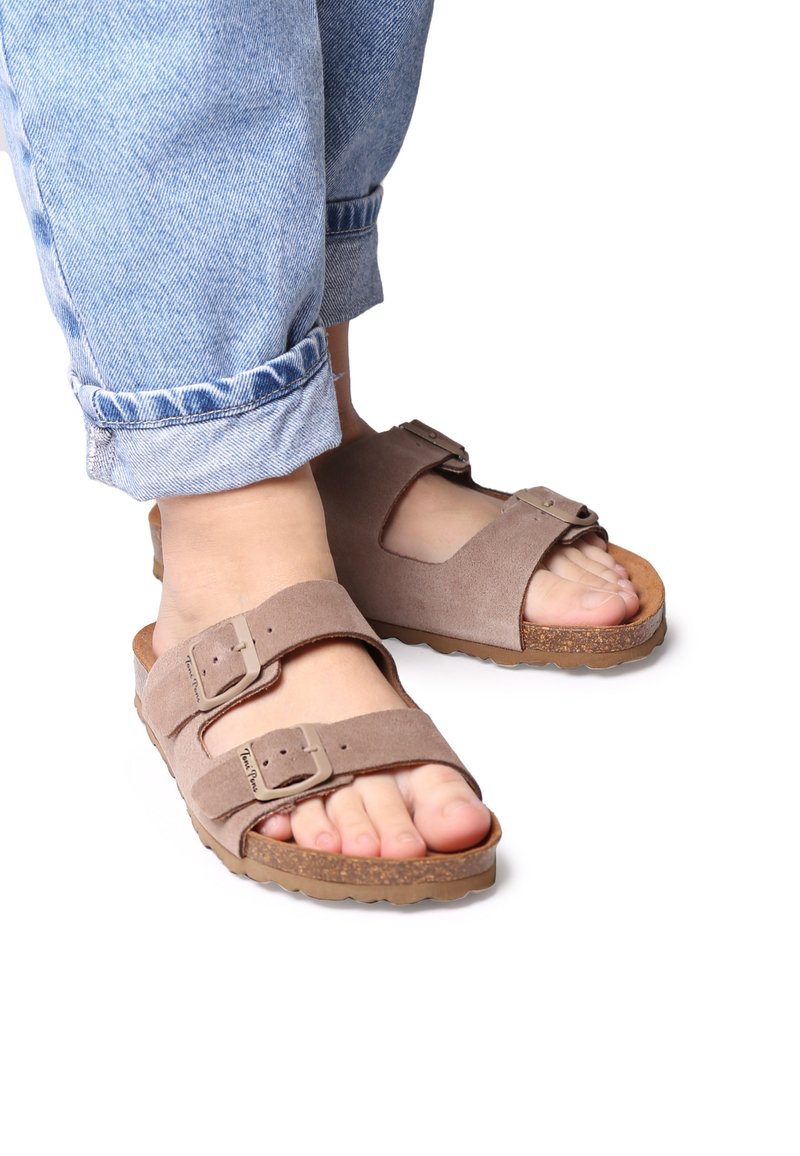 Brown suede sandals with two adjustable straps, cork footbed, and rubber sole. Worn with rolled-up light blue denim jeans.