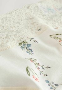 Stof met kantafwerking, voorzien van een bloemenpatroon met blauwe en roze accenten op een zachte, crèmekleurige achtergrond; gladde textuur, verfijnde details.