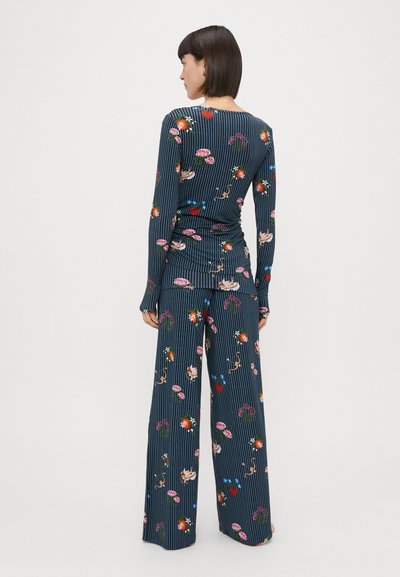 Δύο κομμάτια με πολυχρωμο λουλουδάτο σχέδιο, που περιλαμβάνει ένα εφαρμοστό τοπ με μακριά μανίκια και παντελόνια με φαρδιά πόδια σε σκούρο ναυτικό χρώμα με κατακόρυφες ρίγες.
