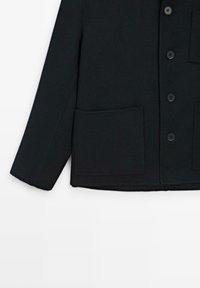 Sort uldblandingsjakke med knaplukning, to store påsyede lommer og lige pasform. Glat tekstur med et klassisk design.