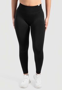 Zwarte legging met een hoge, geribbelde tailleband, gemaakt van een rekbare stof, met een gladde textuur en een aansluitend ontwerp.