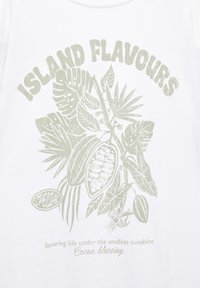 Weißes Baumwoll-T-Shirt mit hellgrüner Grafik, die Kakaoschoten, tropische Blätter und den Text "INSULARE AROMEN" sowie "Kakao-Segen" zeigt.