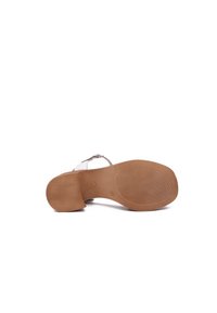 Calzature con suola liscia e grip testurizzato, tacco sottile e design minimalista in colore chiaro con accessori regolabili in metallo argentato.