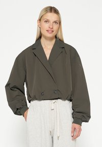 Olijfgroene cropped jasje met een dubbelzijdig ontwerp, oversized mouwen en zwarte knopen; glad, lichtgewicht stof.
