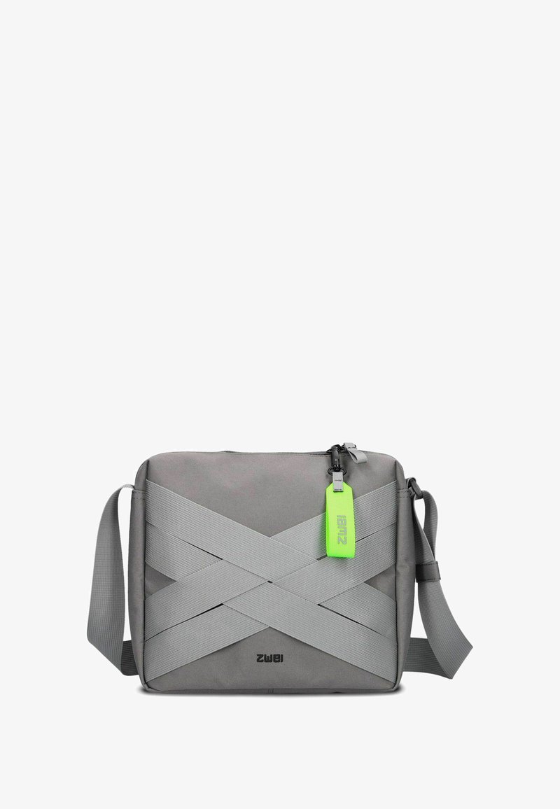 Grau Crossbody-Tasche aus strapazierfähigem Stoff, mit breiten elastischen Bändern auf der Vorderseite, einem Vorderreißverschluss und einem leuchtend grünen Etikett.