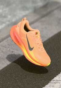 Nike löparsko i klarröd orange, med en texturerad mesh-överdel och svart logga. Har en dämpad sula med neongula detaljer och skosnören.