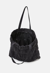 Czarna torba na ramię z tkaniny, z efektowną marszczoną teksturą, dwoma ramiączkami oraz zapinana na zamek kieszeń wewnętrzną. Wewnątrz znajduje się również metka z logo marki.