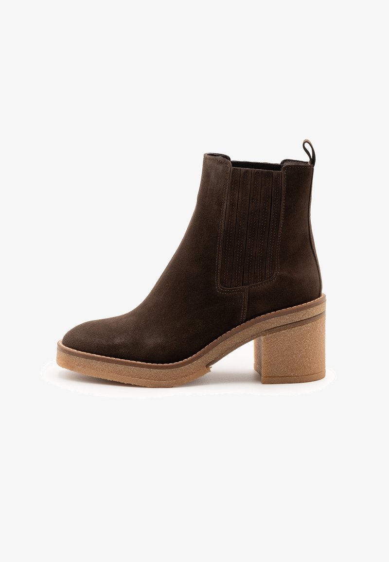 Stivale alla caviglia in suede marrone scuro con pannelli elastici laterali, un anello sul retro e tacco e suola in gomma bloccata beige.