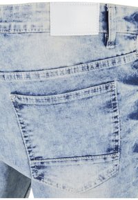 Svetlomodré rifle z denimu so štruktúrovaným, vyblednutým povrchom. Majú zadné vrecko a bielu značkovú nášivku na páse.