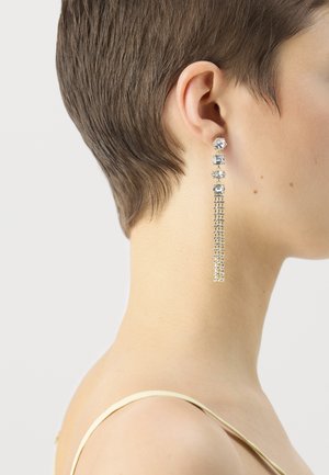 Long drop earrings featuring clear gemstones in various shapes, set in silver-tone metal with a delicate chain design for texture.