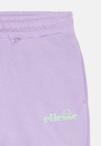 Lila katoenen sweatpants hebben een elastische tailleband en zijzakken. Het linkerlijfje toont een lichtgroen "ellesse"-logo in een afgeronde lettertype.