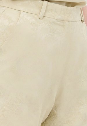 Beige bukser med et subtilt blomsterdesign, skræddersyet pasform og en glat tekstur. Har bæltestropper og en forlommer.