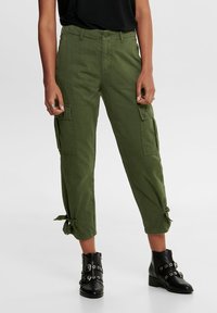 Olijfgroene cargo broek met zijzakken, strikdetails aan de zoom en een relaxed fit. Gepaard met zwarte enkellaarsjes met decoratieve hardware.