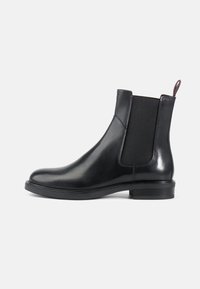Zwarte leren Chelsea-boots met elastische zijkanten, ronde neus en een gladde afwerking. Inclusief een trekband voor gemakkelijk aan- en uittrekken. Platte zool.